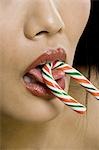 Closeup of woman with red lipstick eating candy cane