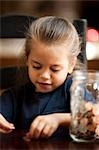 Young girl counting coins from jar