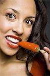 Woman with red lipstick eating red pepper