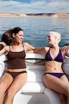 Two women on boat in bikinis smiling