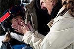 A mother helping her daughter outside in the snow