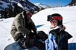 A father helping his daughter with her snowboard