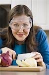 Woman slicing onion with saftey goggles