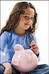 Young girl depositing money in piggy bank