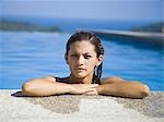 Woman resting on ledge of swimming pool