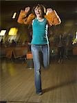 Teenage girl jumping in excitement in a bowling alley
