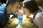 High angle view of a young man and a teenage girl looking at each other and drinking