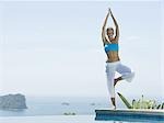 Mid adult woman standing in a tree pose at the poolside