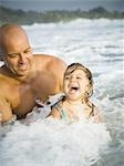 Close-up of a man playing with his daughter in the ocean