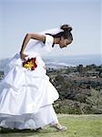 Profile of a bride holding a bouquet of flowers and looking at her shoes