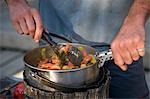 Un randonneur cuisine souper dans un camp le long de la piste Overland Track. .