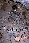 The skeleton of an Inca mummy lies in a cave on Cerro Tunupa overlooking the northern shore of the Salar de Uyuni,the largest salt flat in the world. In front of the mummy are ranged ceramic pots. Local people go to the cave to make offerings to Pachamama,Mother Goddess of the Earth. They place coca leaves and other gifts in the pots and at the same time smoke cocaine cigarettes.