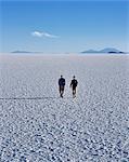 Deux touristes marcher à travers la croûte de sel sans fin du Salar d'Uyuni, le plus grand plat de sel dans le monde à plus de 12 000 kilomètres carrés.