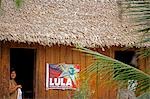 Brazil,Amazon,Rio Tapajos. A tributary of the Rio Tapajos which is itself a tributary of the Amazon. A lady looking out from her wooden house decorated with a political poster for senate candidate Lula in the village of Maguari.