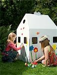 Girls painting a cardboard wendy house