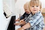 Zwei junge Kleinkinder sitzen an einem Klavier