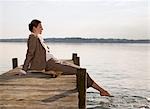 woman sitting on pier at lake