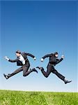 businessmen jumping in field