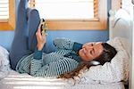 Woman Lying on Bed Listening to Music