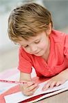 young boy on floor painting with pen