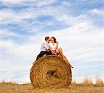 woman and man kissing on hay bale