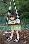 Little girl playing on wood swing