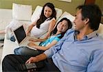Familie entspannend auf Sofa im Wohnzimmer, Tochter mit Laptop