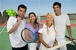 Four mixed doubles tennis players at net on tennis court, portrait