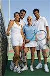 Four mixed doubles tennis players at net on tennis court, low angle view