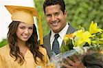 Graduate with flowers and father outside, portrait