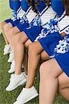 Cheerleaders sitting on bench, (low section)