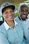 Senior couple in golf course, smiling, (portrait)