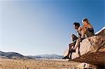 Climbers sitting on Rock Looking at Desert