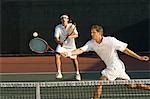 Tennis Player stretching, Swinging at Ball near tennis net, doubles partner standing behind