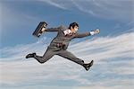 Business man running with briefcase mid-air outdoors