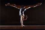 Gymnaste (13-15) faire diviser l'appui tendu renversé sur la poutre d'équilibre, vue latérale