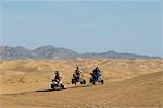 Men riding quad bikes in desert