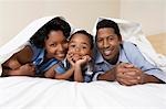 Family with son (3-6) lying underneath sheet, portrait