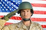 Soldier saluting in front of United States flag, (portrait)