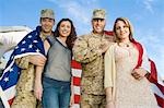 Military couples embracing outdoors, (portrait)