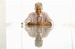 Businessman sitting at table, smiling, portrait