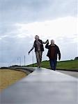 Senior couple walking on wall, holding hands