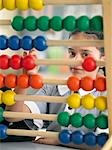 Elementary schoolgirl looking through abacus, sitting in classroom