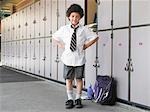Elementary schoolboy standing by school lockers, portrait