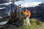 Hikers climbing out of helicopter on mountain peak