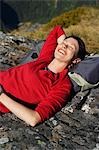 Woman laying on backpack on boulders