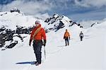 Three hikers joined by safety line in snowy mountains