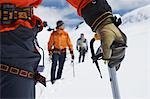 Hikers using walking sticks in snowy mountains, mid section on front man