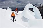 Two hikers going past ice formation in mountains, back view
