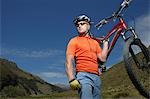 Cyclist carrying bike in countryside